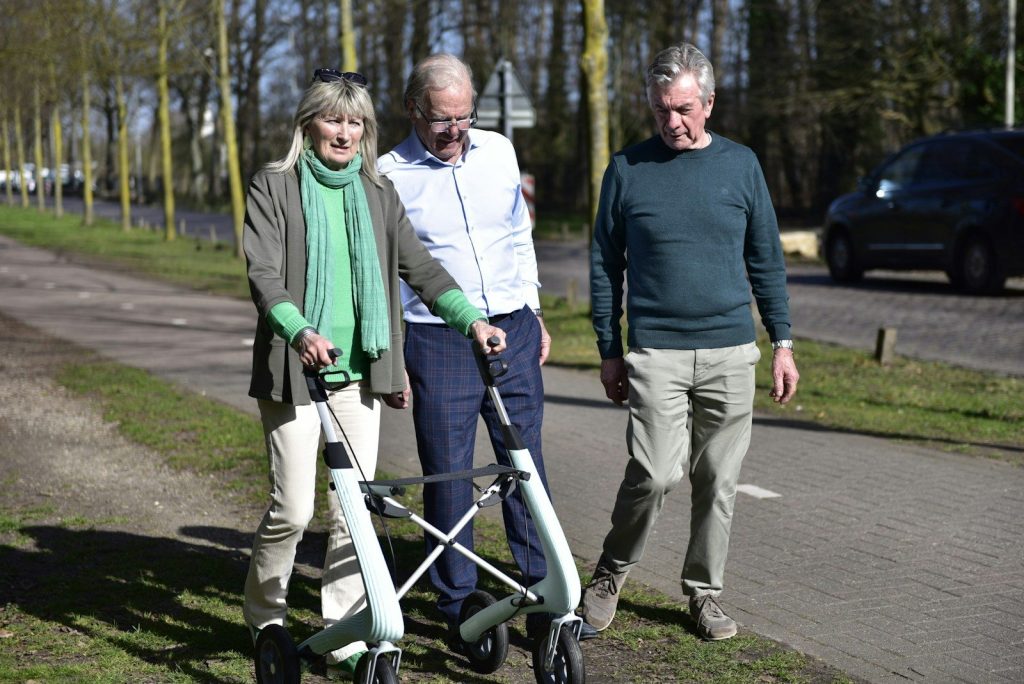 Three people with a walker on a path