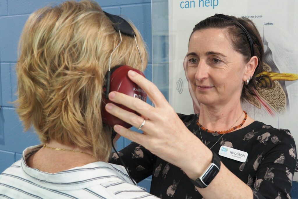 An audiologist helps a woman with a hearing test.